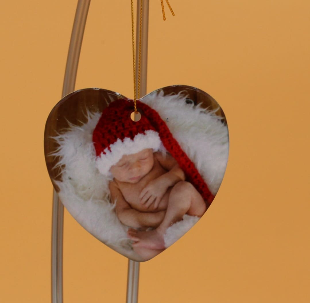 A heart shaped ornament with a picture of a baby in it.