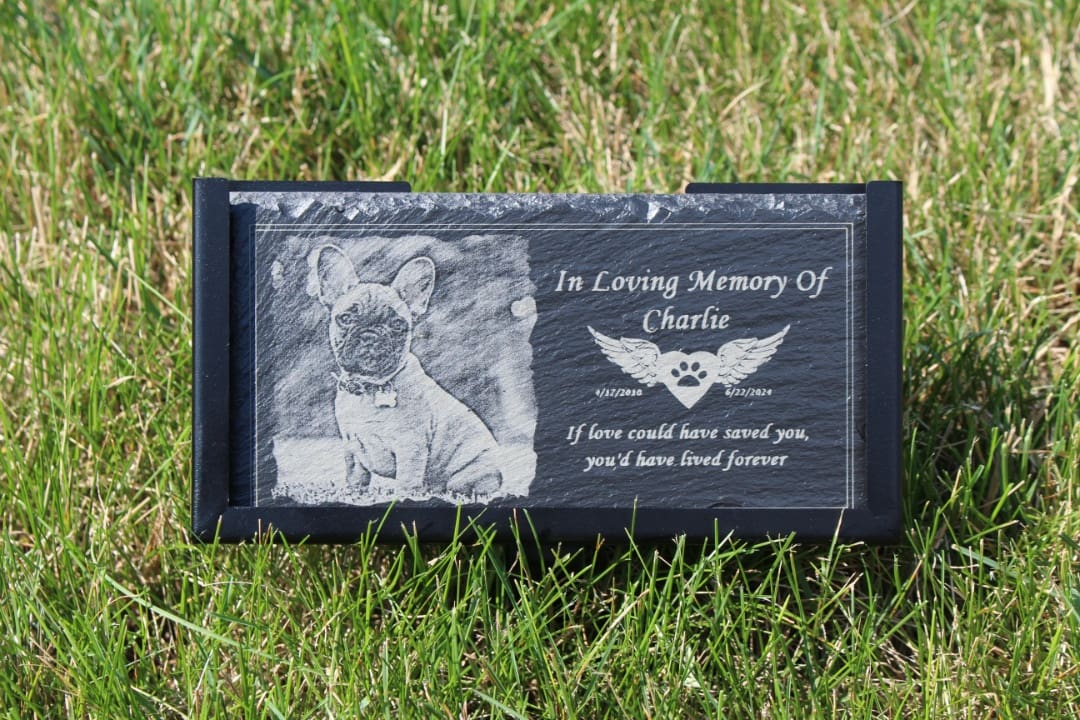 A memorial stone with an image of a dog and the words " in loving memory of charlie."