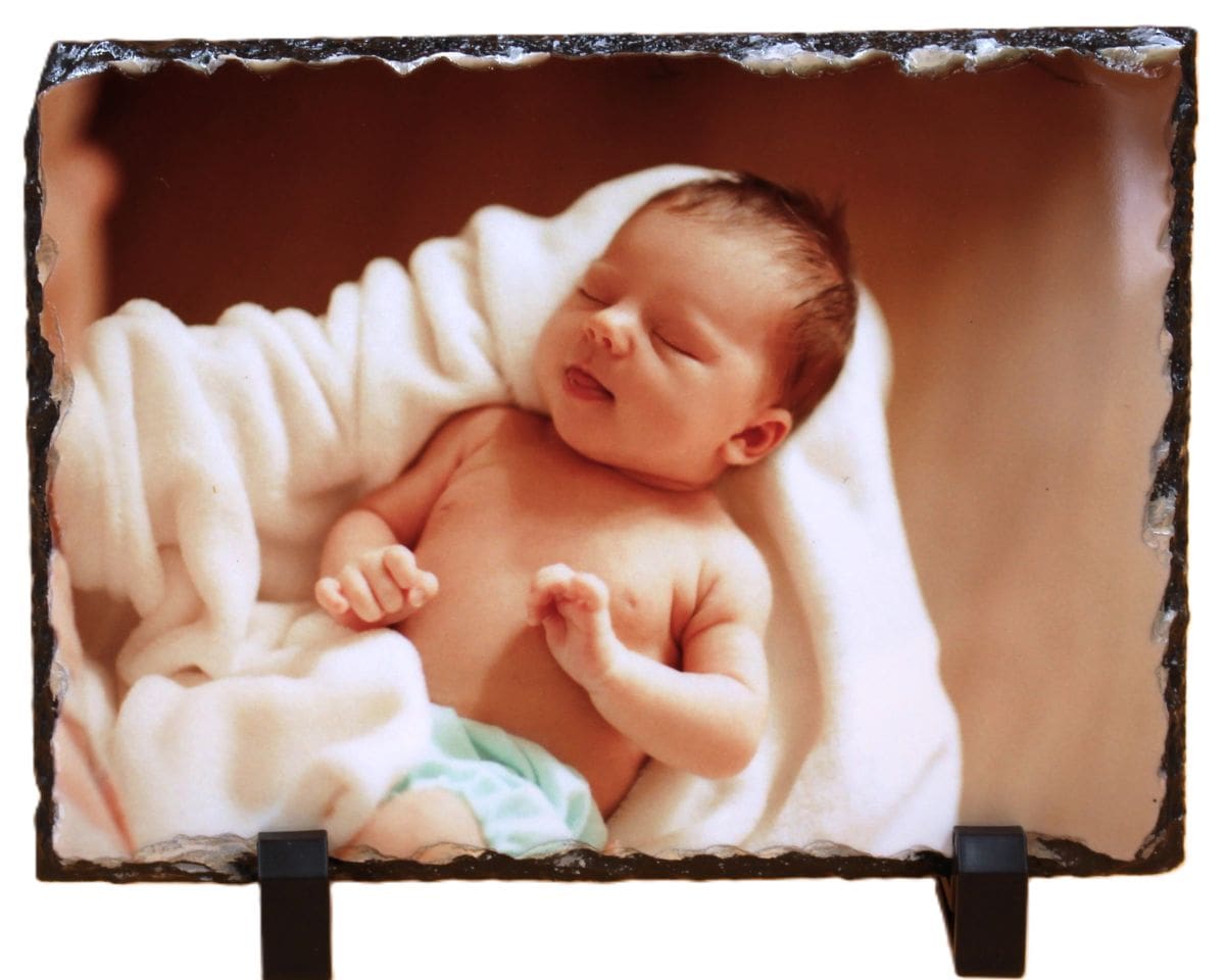 A baby laying in the blanket on top of a rock.