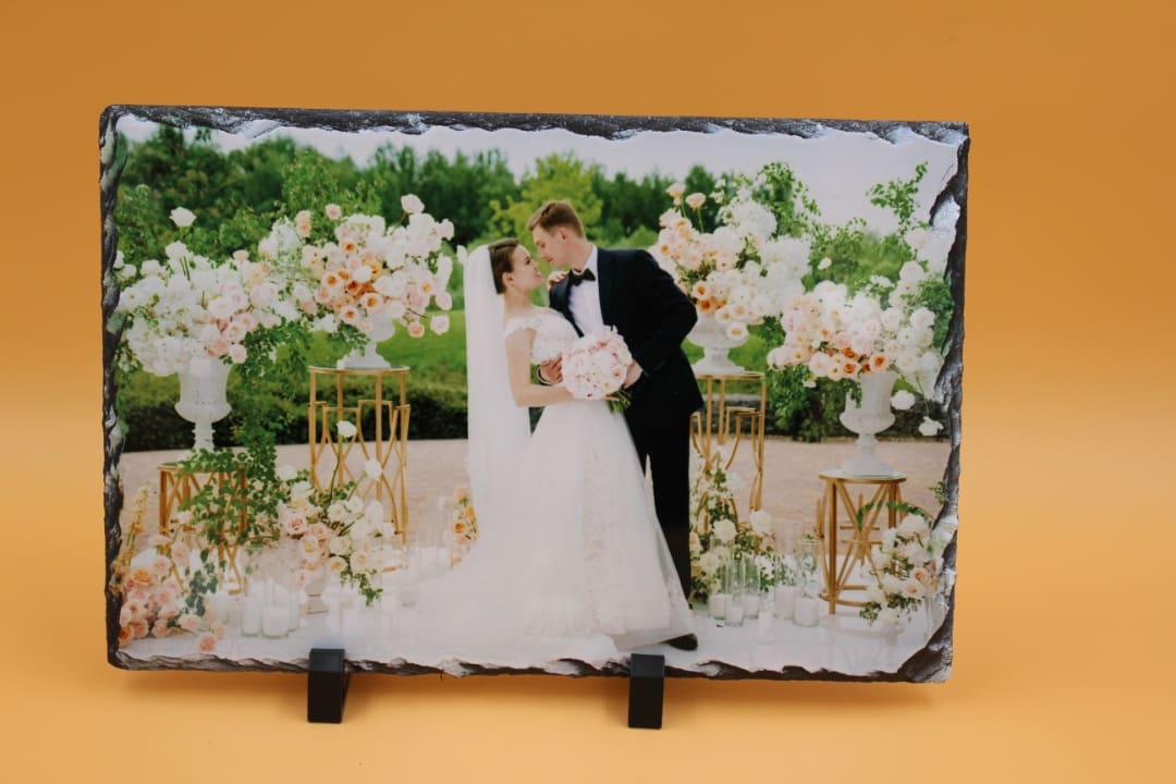 A couple kissing in front of flowers on a stone.